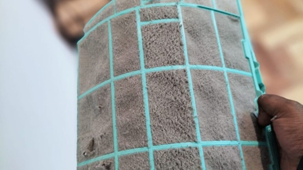 Dirty air conditioner filter being removed during routine aircon servicing.